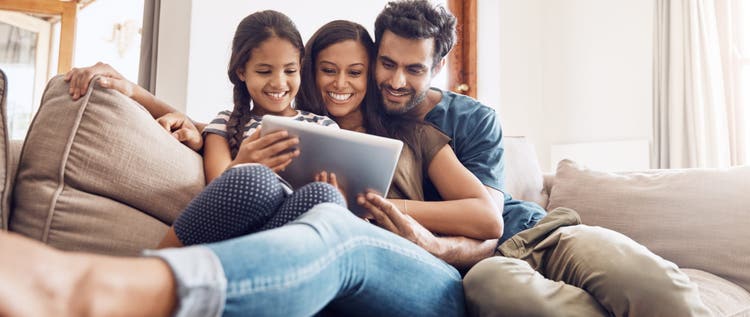 Shot of a mother and father using a digital tablet with their daughter on the sofa at home