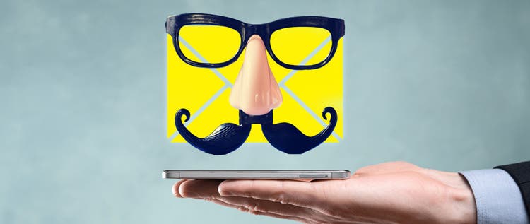 A yellow email icon with a false mustache and glasses floating over a cellphone resting on an open hand