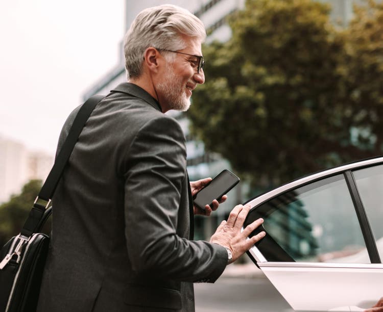 Older man in business suit getting into a waiting car.