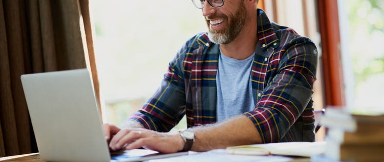 Man seated at computer at home happily typing.