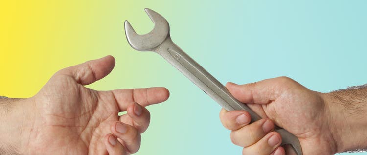 A man's hand giving another man's hand a wrench against a yellow and blue background.