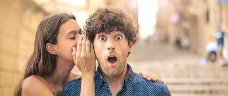 woman whispering secret to a man