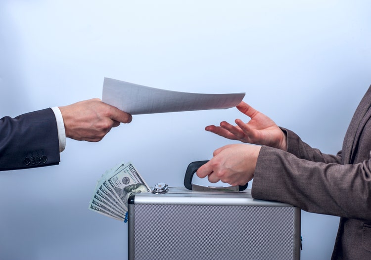 Woman in suit gives metal briefcase with dollars, man gives her important documents. Conception of safe storage and protection of cash, the exchange process. Financial theme. Horizontal view.